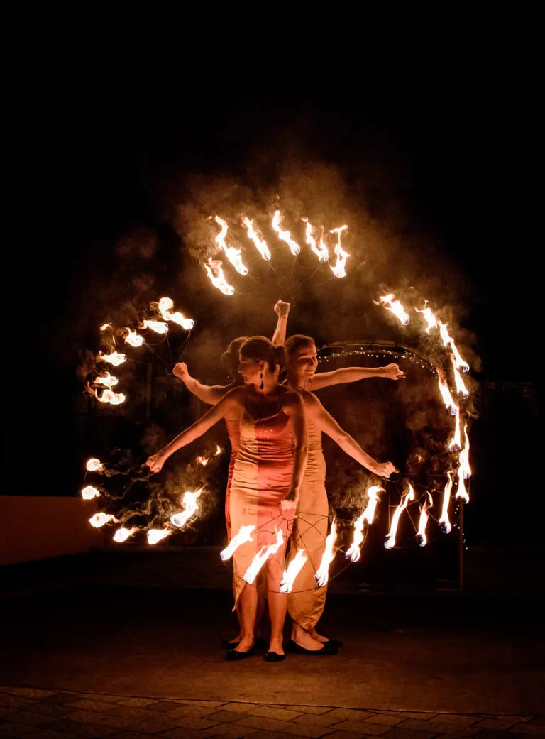 Dancers whirl fire sticks in their hands during the show outside