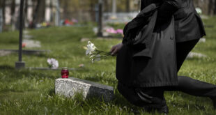 man paying respect tombstone cemetery