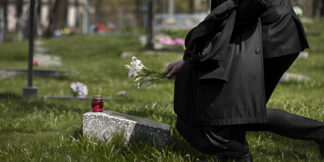 man paying respect tombstone cemetery